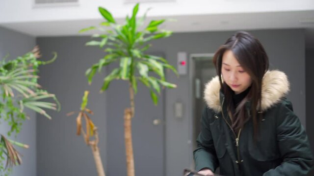 young asian american woman getting ready to leave, puts on a jacket grabs a notebook and walks away, video 4k
