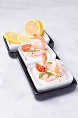 Delicious shrimp canapes with tomato and arugula on a light background. Festive appetizer with seafood.