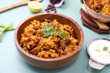 Indian cuisine - Kidney Beans Biryani, Rajma Pulao. Garnished with chopped coriander, and lemon wedges. Rajma biryani served with dahi. Along with copy space. Rajma Chawal flatlay.