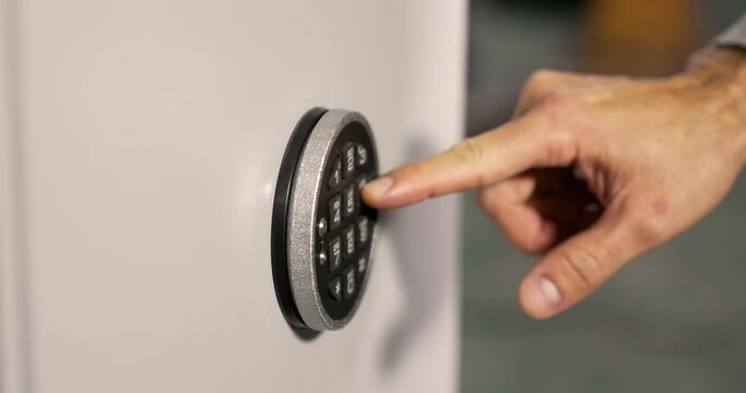 Close-up of a man's hand inserting a security code into the safe to open it. Then the security safe is opened with the electronic handle. 