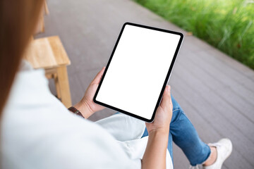 Mockup image of a woman holding digital tablet with blank white desktop screen in the outdoors