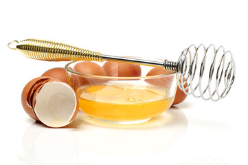 Wire whisk and brown eggs on white background 
