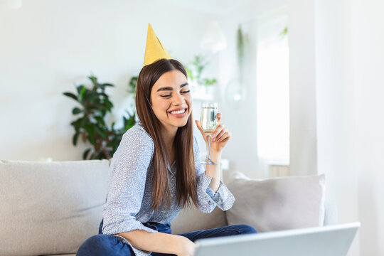 Copy space shot of a cheerful young woman having a birthday celebration event with a friend over a video call. She is making a celebratory toast with a glass of white wine towards laptop camera.