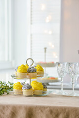 Dessert stand with tasty cupcakes and glasses on table
