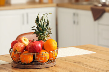 Basket with fresh fruits on wooden table in kitchen