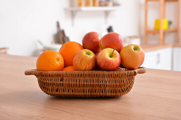 Basket with fresh fruits on wooden table in kitchen