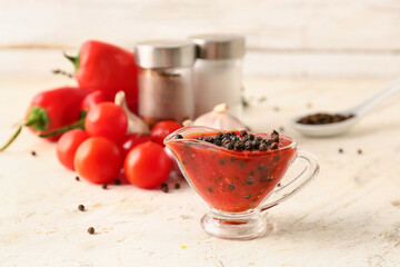 Gravy boat with peppercorn sauce and ingredients on light background