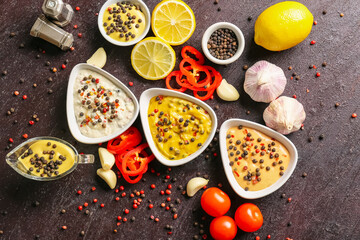 Bowls with different sauces and ingredients on dark background