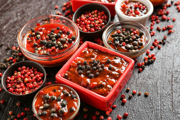 Bowls with peppercorn sauce on dark background, closeup
