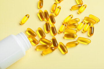 Bottle with fish oil capsules on color background