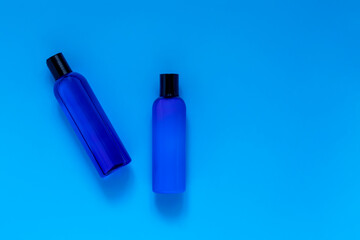 Cosmetic bottles with refreshing shampoo and lotion on a blue background, top view. Packaging for branded products.Blue on blue.