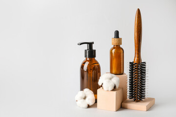 Hair brush and cosmetics on light background