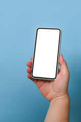 Cropped shot man holding mock up mobile phone over blue background.