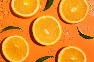 Slices of ripe orange on color background with water splashes