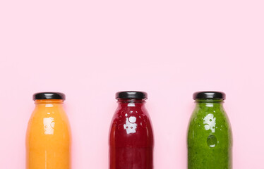 Bottles of healthy smoothie on color background