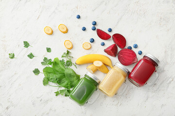 Mason jars of healthy smoothie and ingredients on light background