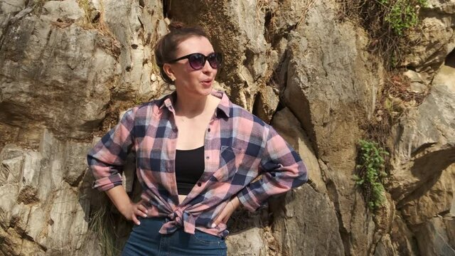Girl Breathing Hard after Difficult Climb on Mountain Trail. Travel. New Places. Leaned against the Rock. Resting. Camera Flight. Stands with Hands on Sides. Difficult Ascent. Forest Trail. Mountains