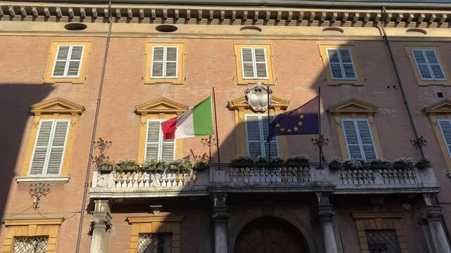 Italian and european flags waving in the wind on the balcony of government building. concept for tourism, patriotism, international business, policy, trade
