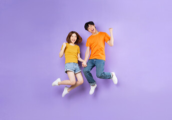 Fototapeta na wymiar Portrait of a couple jumping up, isolated on purple background