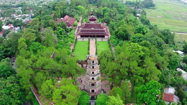 Aerial Tilt Up Shot Of Famous Thien Mu Pagoda Amidst Green Trees, Drone Descending Over Popular Landmark Against Sky - Hue, Vietnam