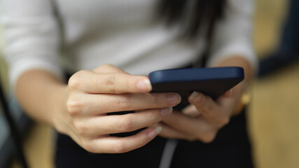 Female texting massage on smartphone in her hands