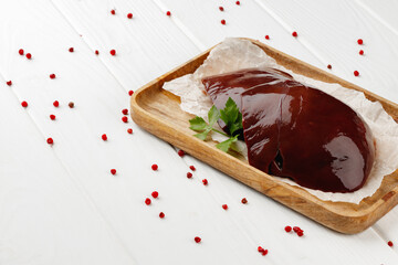 Raw beef liver on wooden board on table