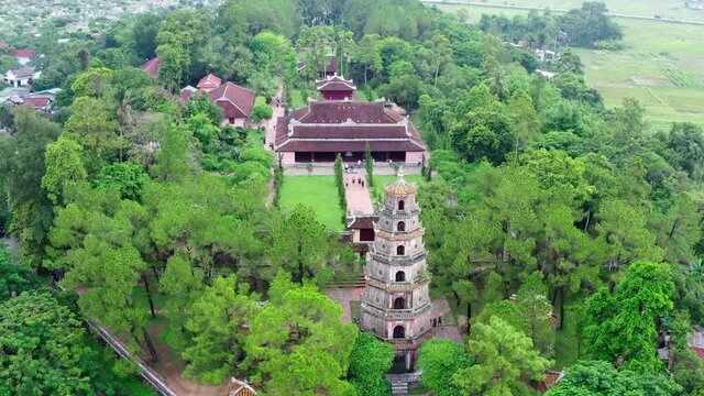 Aerial Panning Shot Of Tourists At Thien Mu Pagoda Amidst Green Trees, Drone Flying Near Popular Buddhist Temple - Hue, Vietnam