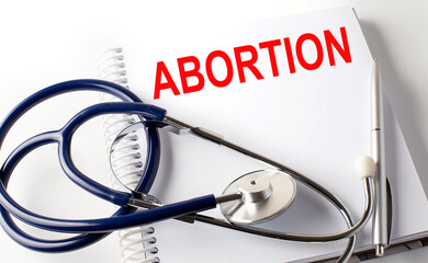 Text ABORTION on a white background with stethoscope. Medical