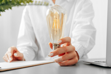 Woman in white shirt holding light bulb in hand