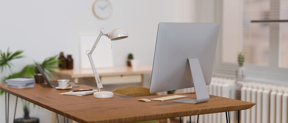 Wooden office desk with computer, lamp, supplies and decorations, 3D rendering