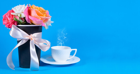 Fototapeta na wymiar Bouquet of rose flowers, white coffee cup with steam on blue background. Copy space