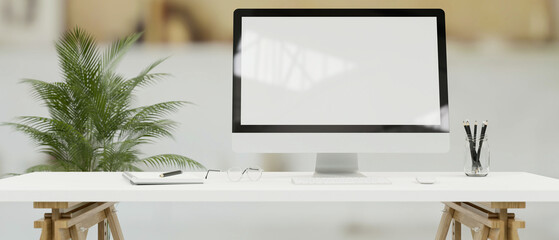 Desktop computer with mock-up screen on white desk in simple office room, 3D render