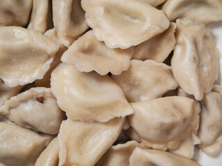Serving of traditional Russian boiled dumplings on a white plate . Close up. Classic Eastern meat and dough dish.