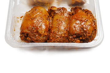 Raw uncooked Asian spice marinated chicken fillets in a plastic tray. Poultry product. Meat industry, Summer barbecue range. Meat in marinade with herb, oils and sauce. Isolated on white