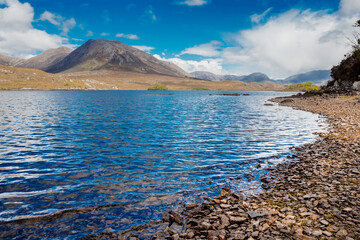 Lake Derryclare Lough in Connemara, county Galway, Ireland. Irish nature landscape. Beautiful scene with water, mountains and blue cloudy sky. Nobody. Popular tourist landmark