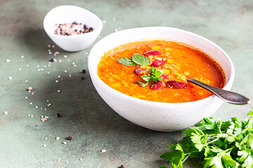 A bowl of homemade red bean and lentil soup, bread and parsley on stone background. Vegetable spicy soup.