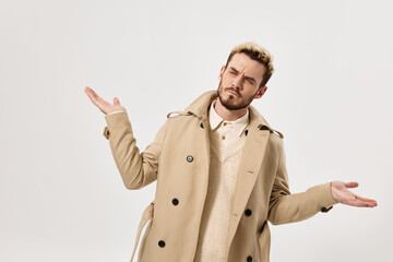 handsome man throws up his hands beige coat autumn style studio