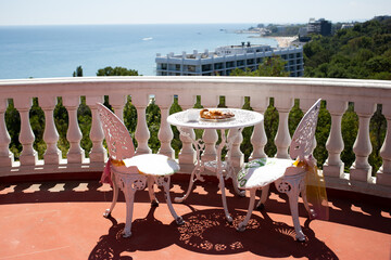 Chairs and a table are on the veranda with stunning sea view. Coffee, cakes and biscuits on a plate. Bulgaria, Golden Sands