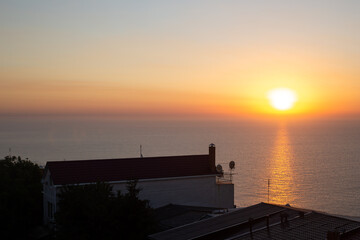Fototapeta na wymiar Golden sunrise sunset over the sea near port and city