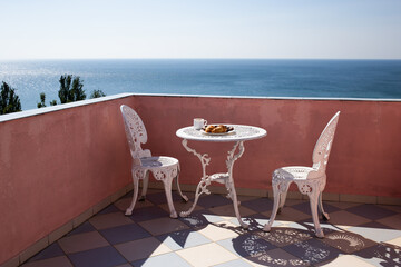 beautiful terrace with chairs and a table with a beautiful sea view. Coffee, cakes and biscuits on a plate. Bulgaria, Golden Sands