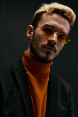stylish man with glasses orange sweater coat black background 