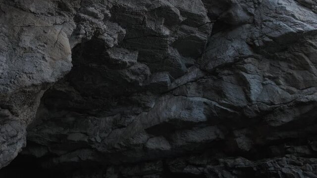 Mystical grey cave tunnel hole with large rocks over sea water under bright sunlight with dark shadows on summer day. The greatness and tranquility of nature. Water cave 