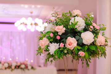 Elegant central floral wedding arrangement in foreground. Concept of wedding events. Wedding floristry. Luxury and beauty. Important life events.