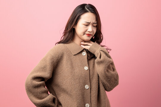 Oriental beauty with sore throat on pink background