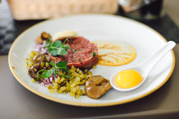 Traditional appetizer with tartare and egg and fresh vegetables on plate in restaurant. Concept of delicious and healthy food. Enjoy your food. Beautiful moments.
