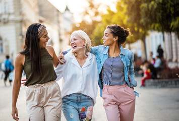 Three young women walking together on city street.