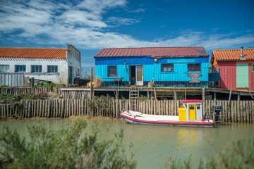 Colourful oyster huts and fishing boat at Atlantic coastal village harbour on Oleron Island,...