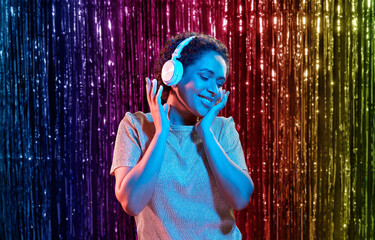 nightlife, technology and people concept - happy young african american woman in headphones...