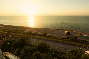 RUSSIA, YEYSK - AUGUST 20, 2016: View of the Sea of Azov and the small tourist town of Yeysk from above of the Ferris wheel at sunset. Russia, Sea of Azov, Krasnodar Territory, Yeysk. - obrazy, fototapety, plakaty