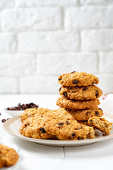 Homemade oatmeal cookies with raisins in a white plate on a light background closeup